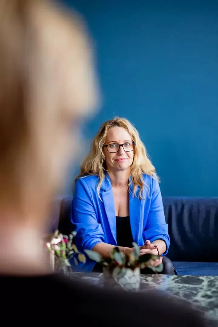 Jennie i blå kavaj lyssnar på en klient i ett coachsamtal