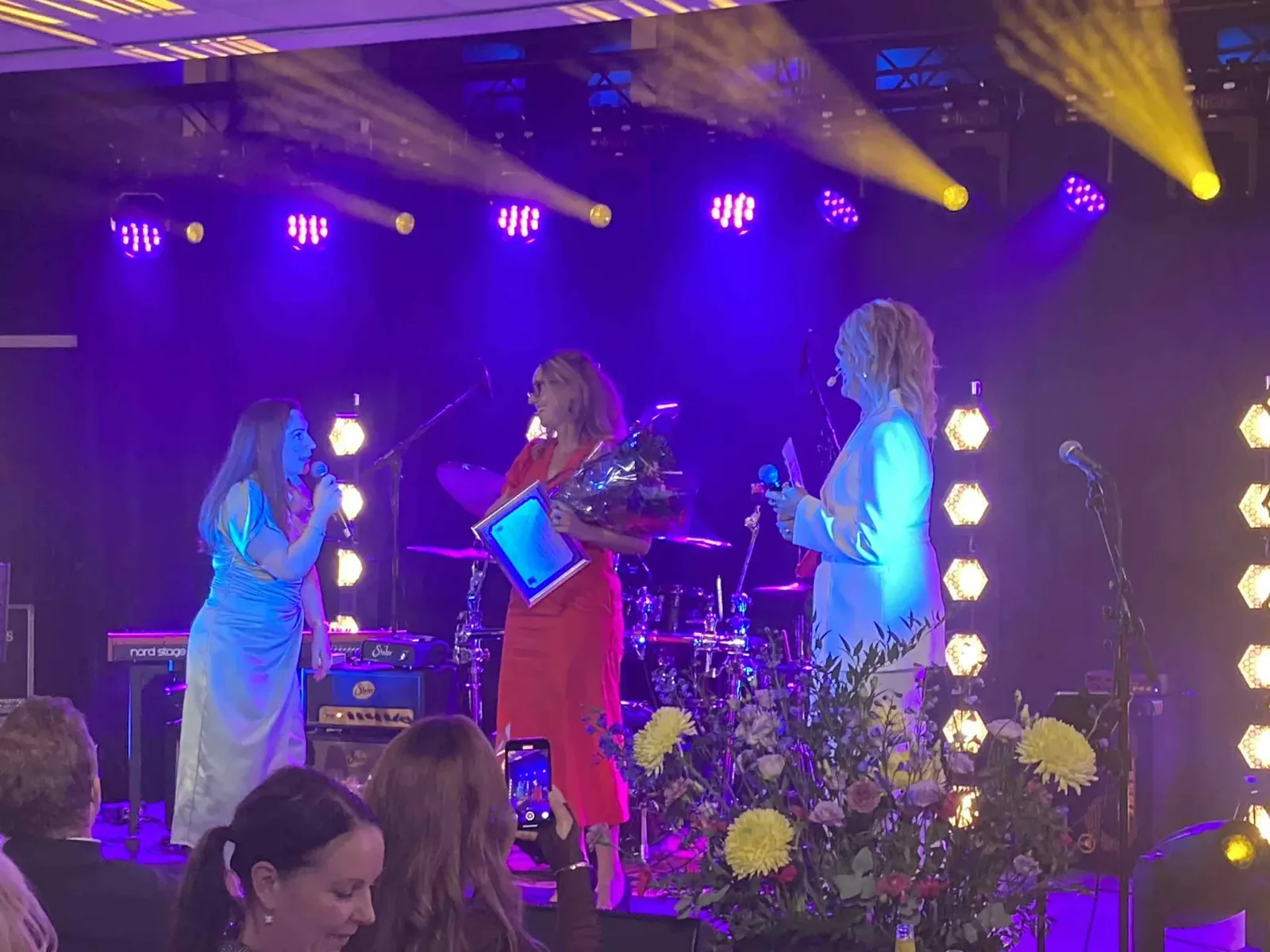 Jennie tar emot priset Årets Nyföretagare på scen med blommor och diplom